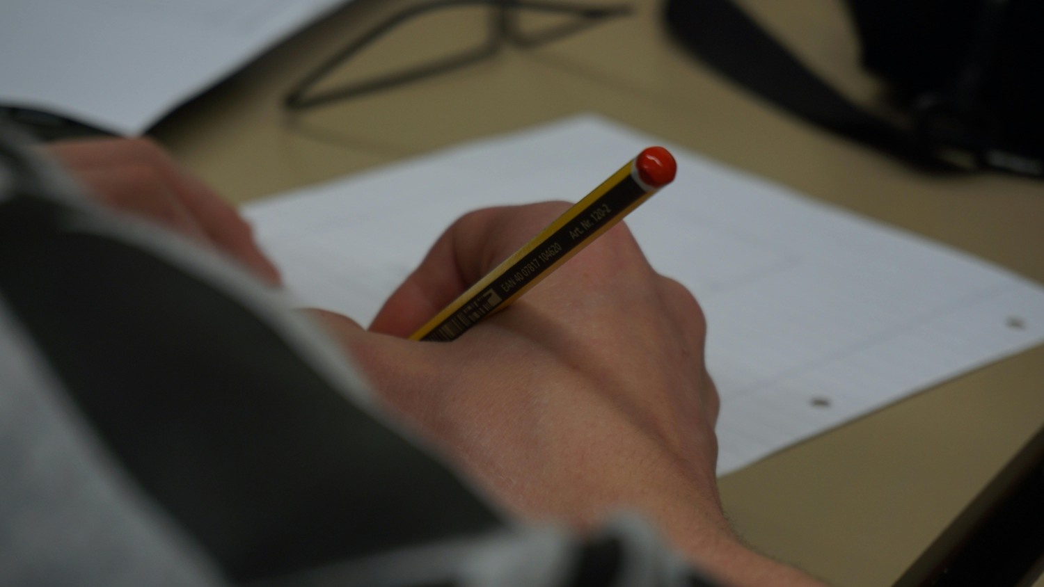 Close-up of a writer drafting notes with a pencil on a desk, shallow depth of field.
