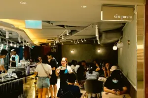 Wide interior shot of Sio Pasta Raffles Place dining area with warm lighting, counter seats, and casual lunch crowd in Raffles City