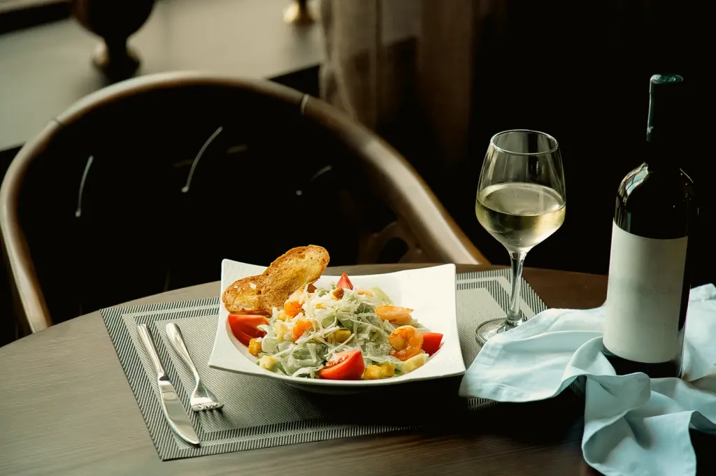 Eye-level close-up shot of a fine dining table in Singapore featuring a plated gourmet salad, wine glass, and elegant table setting, representing an upscale fine dining restaurant experience for special occasions.