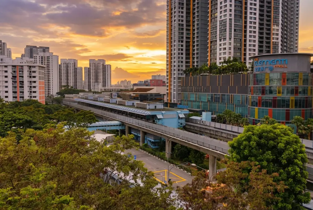 Elevated view of Clementi Town Centre at sunset, showcasing the MRT train tracks, The Clementi Mall, and surrounding high-rise residential buildings.