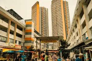 Street-level wide-angle view of Clementi Town Centre in Singapore with bustling hawker stalls, pedestrians, and high-rise HDB flats showcasing local food culture and Nasi Padang heritage
