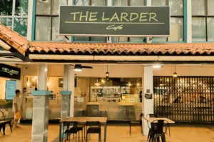 The Larder Cafe exterior in Toa Payoh with rustic tiled roof, warm lighting, and outdoor seating area, captured in a straight-on eye-level shot highlighting the storefront signage and inviting facade.