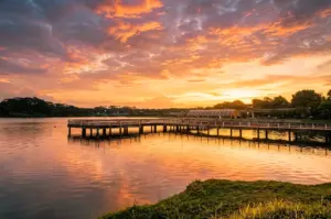 Wide-angle eye-level shot of Lower Seletar Reservoir jetty at sunset with golden sky reflections on calm water in Yishun Singapore