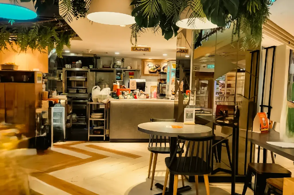 ye-level medium-wide shot of Greendot interior with cashier counter, modern decor, and cozy plant-based restaurant ambiance in Junction 8