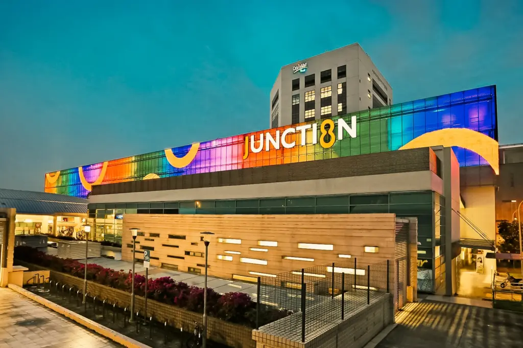 Low-angle wide shot of Junction 8 mall in Bishan Singapore with colorful illuminated facade, central hub for dining and shopping near Bishan MRT