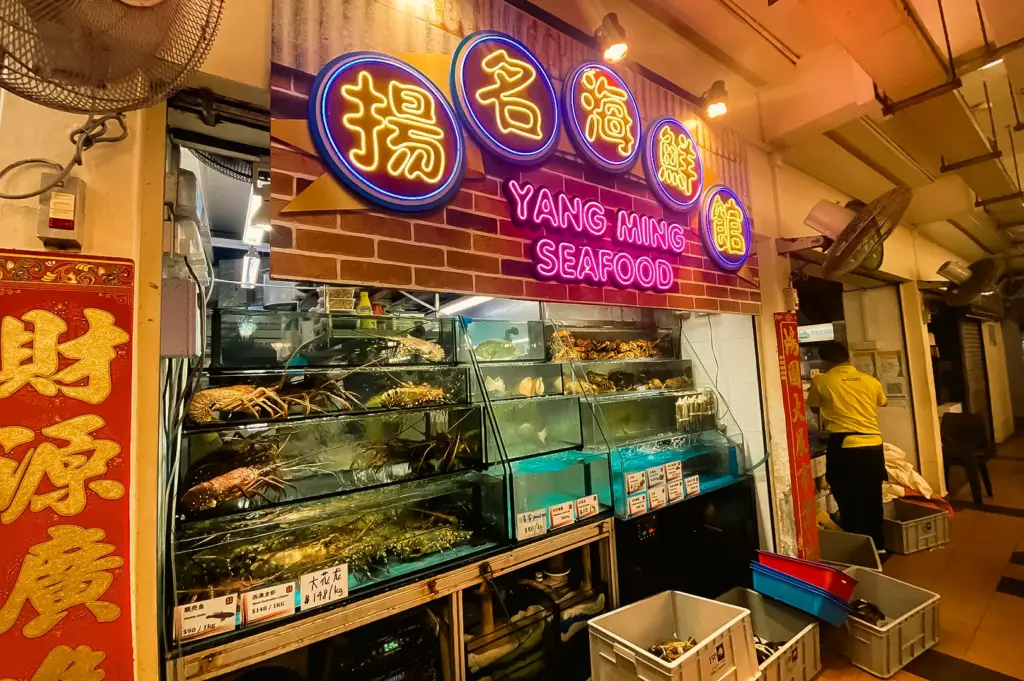 Eye-level interior shot of Yang Ming Seafood stall in Bishan with live seafood tanks and neon signage, popular zi char dining spot in Singapore heartland