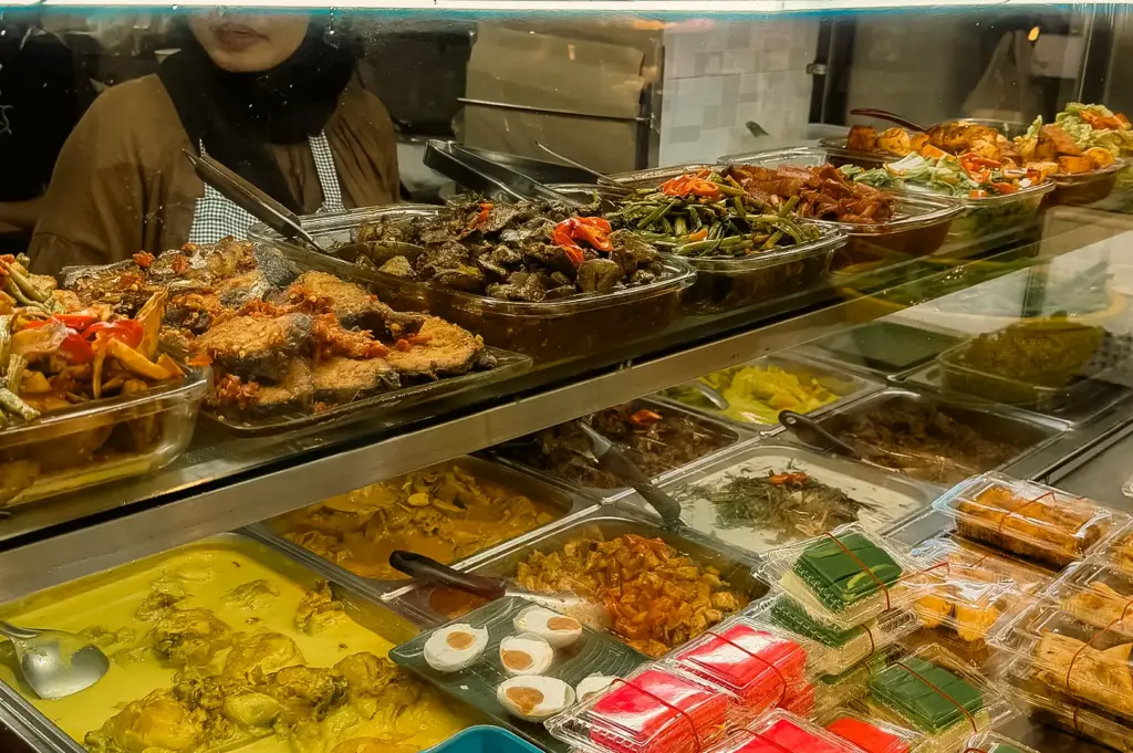 Slightly high-angle view of a Nasi Padang food display counter with assorted curries, rendang, vegetables, and coconut-based dishes inside a Singapore hawker centre in Clementi