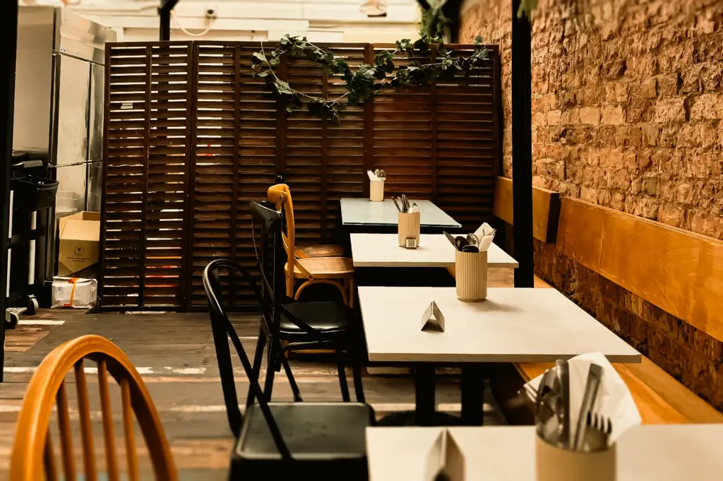 Eye-level wide shot of Clovelly Serangoon minimalist cafe interior with wooden tables, brick wall decor, and natural light in a cozy neighborhood brunch spot in Singapore