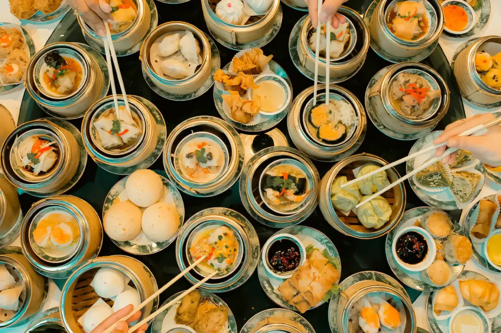 Top-down overhead shot of assorted dim sum feast in bamboo steamers, featuring dumplings, buns, and small plates on dining table, authentic yum cha dining Singapore