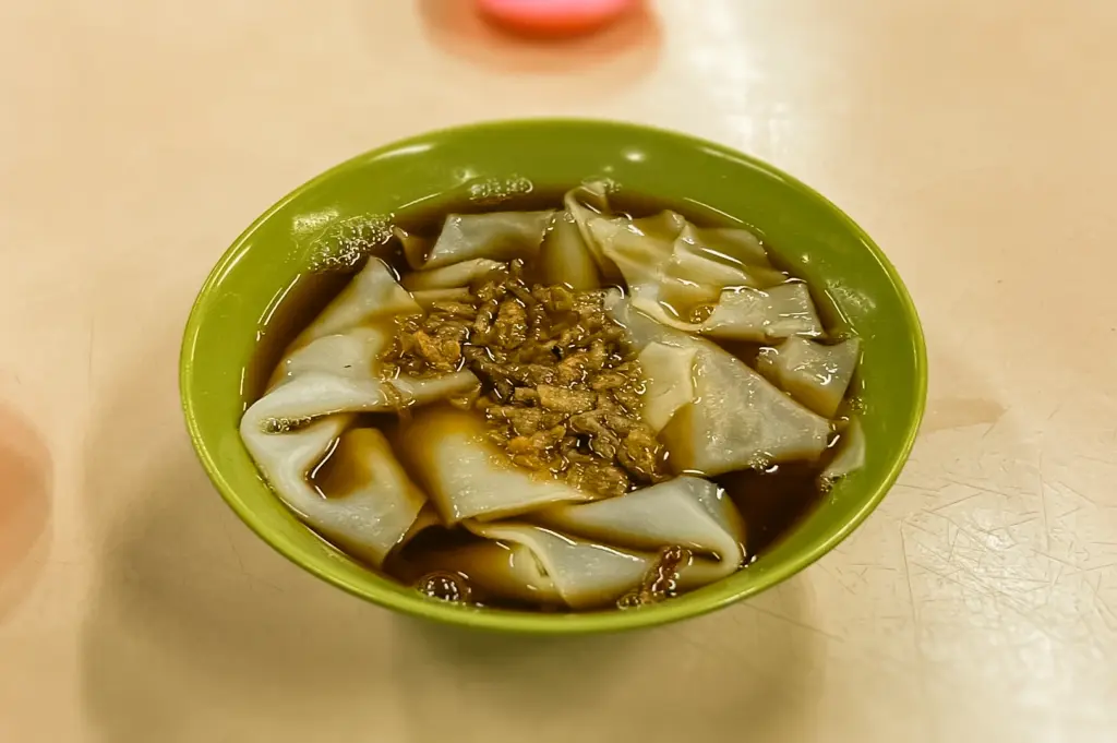 Top-down close-up shot of traditional kway chap noodles with soy broth in a green bowl, affordable hawker food commonly found in Bishan Singapore