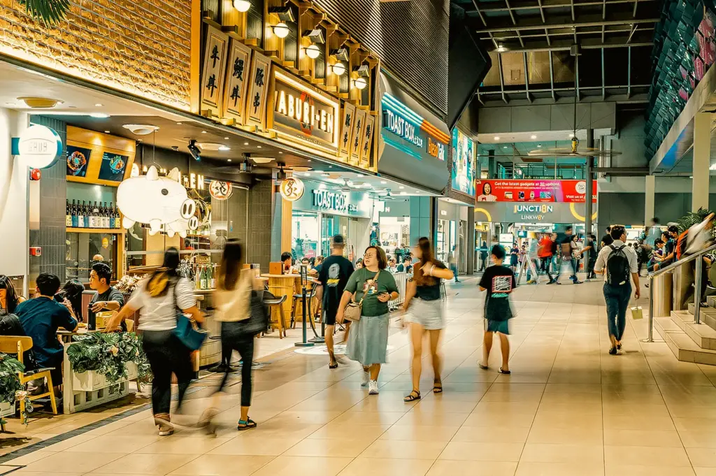 Eye-level street-style shot of busy indoor dining walkway near Junction 8 with cafes and restaurants, capturing everyday food culture in Bishan Singapore