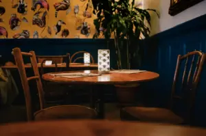 Quiet café interior with a neatly set wooden table, soft lighting, and decorative wallpaper, photographed from a slightly low table-level angle during early pre-crowd dining hours