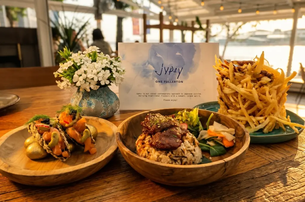 Medium shot of Jypsy One Fullerton signature dishes including salmon tacos, Wagyu fried rice, and truffle fries, showcasing Japanese contemporary cuisine at a Marina Bay waterfront restaurant.