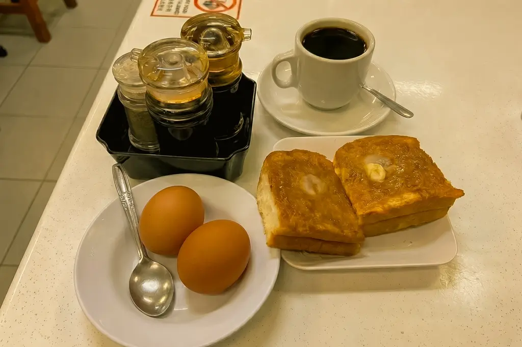Traditional Singapore breakfast at YY Kafei Dian with kaya toast soft boiled eggs and kopi coffee, top-down flat lay shot angle