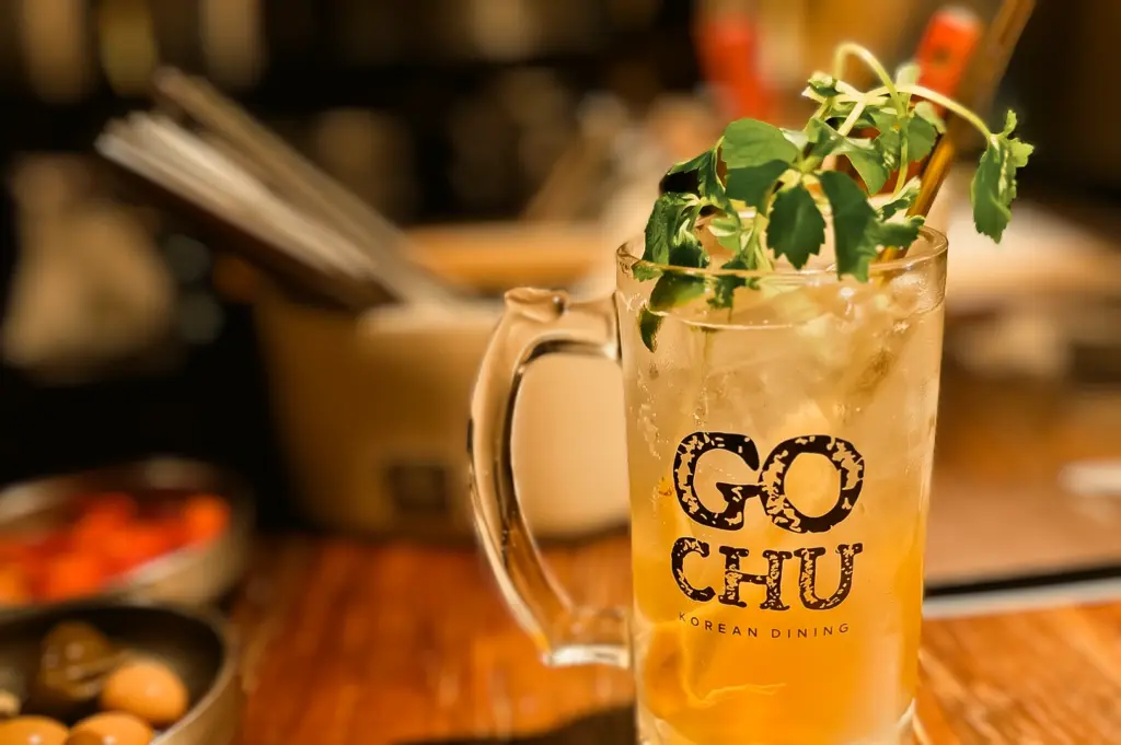 Close-up shot of Gochu Korean Dining ginseng highball cocktail in frosty glass mug with herbs garnish at Korean BBQ restaurant Singapore