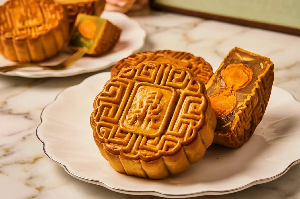 Angled close-up shot of traditional baked mooncake with salted egg yolk filling on white plate, Mid Autumn Festival Singapore