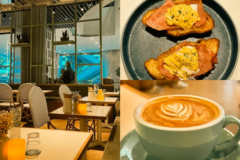 Left: wide-angle eye-level shot of a cozy café interior with square tables, cushioned chairs, warm ambient lighting, candles, and a glass partition revealing a view of an exterior walkway; Upper Right: top-down close-up of two open-faced croissants topped with ham, poached eggs, and a piped yellow sauce on a dark ceramic plate; Lower Right: close-up eye-level shot of a latte in a pastel cup with heart-shaped latte art, resting on a saucer with soft café lighting.