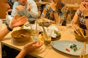 Eye-level shot of friends reuniting over a shared meal at a casual restaurant in Pasir Ris, capturing meaningful conversations, nostalgia, and lasting friendships.