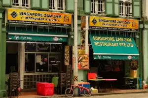 Eye-level wide-angle view of Singapore Zam Zam Restaurant on North Bridge Road in Kampong Glam, Singapore, a historic halal Indian Muslim restaurant famous for mutton murtabak, nasi briyani and traditional Singapore dining.