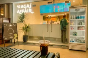 Low-angle eye-level view of an iced drink on a bench outside An Acai Affair at Robertson Quay, Singapore, capturing a quiet after-work pause, café culture, and the comfort of returning to a familiar acai shop. [The Day I...Back Here | Word]
