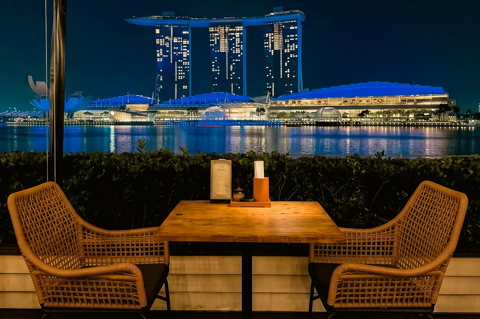 Romantic waterfront dining at Jypsy One Fullerton Singapore with Marina Bay Sands night skyline view and outdoor table setting, eye-level centered shot