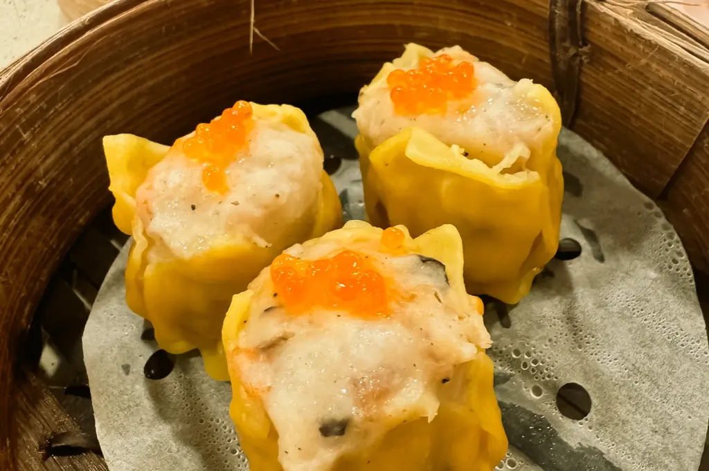 Macro close-up of Kimly Dim Sum siew mai at Kimly Coffee Shop Pasir Ris, featuring steamed pork dumplings topped with bright orange fish roe, a popular dim sum snack in Singapore's neighbourhood coffeeshop scene.