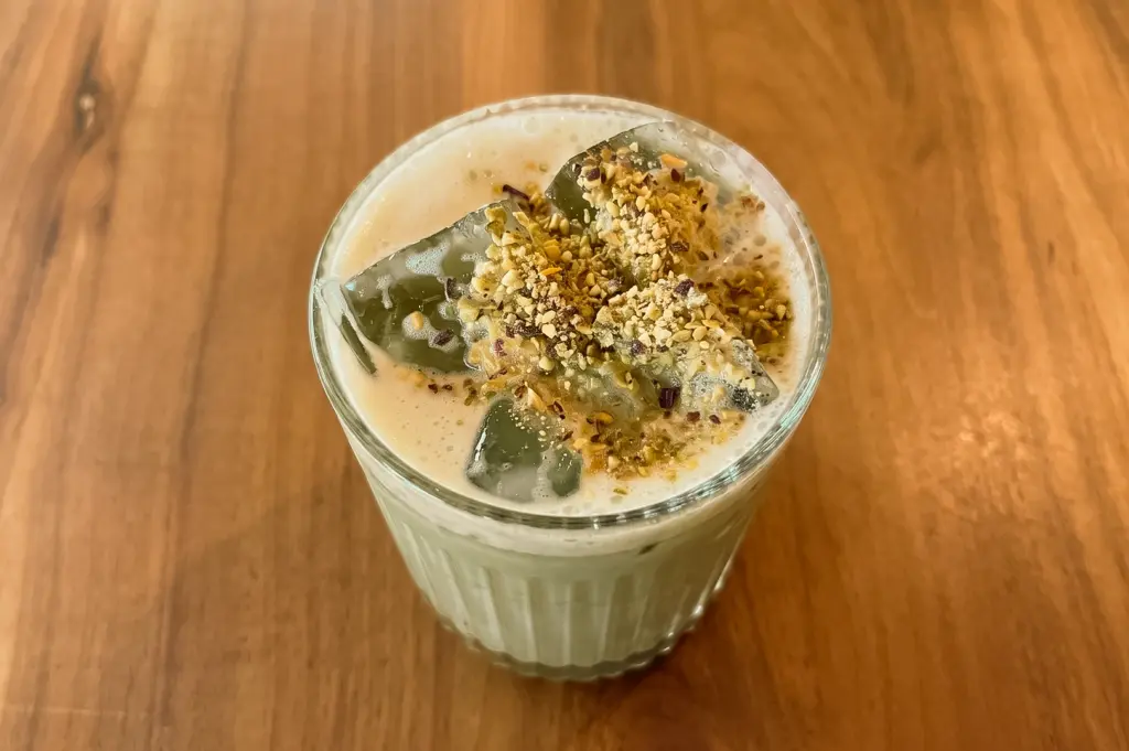 Top-down close-up shot of Lola Faye Cafe's Pistachio Cloud Latte, topped with crushed pistachios and jelly pieces, served as a signature specialty drink in Singapore.
